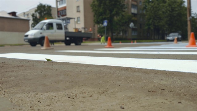 在城市街道的十字路口，工人们用油漆在人行道上画上斑马线视频素材