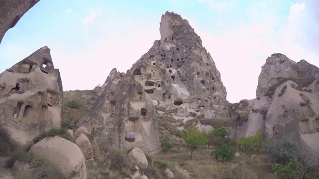 乌奇萨的低角度倾斜视图，美丽的顶峰岩石形成的火山侵蚀岩在火山景观被岩石胡毒教，清真寺，教堂，和房子，在卡帕多西亚，土耳其视频素材