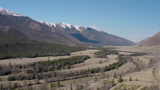 从四轴飞行器上看，群山和雪白的山峰，蓝天为背景。鸟瞰图。视频素材