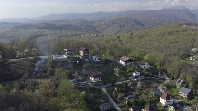 村舍在青山绿树丛中，在夏季的山景中。空中环视乡村房屋，山谷背景覆盖夏季绿色森林视频素材