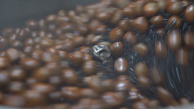 美食视频沙粒烤栗子场景。把干沙子放进大托盘里，热沙子被加热，这有利于让栗子成熟，4K分辨率的近距离拍摄。视频素材