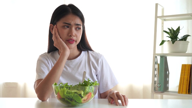 健康食品和素食的概念，饮食，节食，不快乐的节食亚洲女孩有一个无聊的表情当她吃蔬菜。视频素材