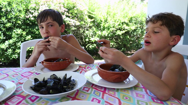 孩子们午餐时吃海鲜贻贝。偶然的孩子在饭桌上吃鼹鼠视频素材