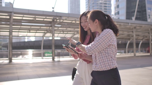 两位亚洲女商人在上班路上使用智能手机视频素材