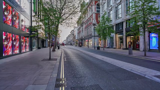 沿着英国伦敦市中心的牛津街(Oxford Street)，黄昏时分人潮稀少，交通繁忙视频素材