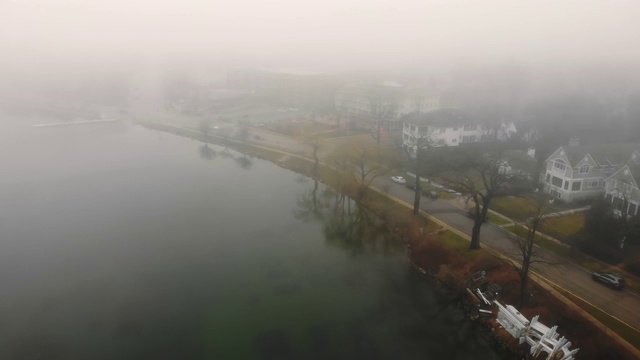 在大雾多云的天气中飞过湖面。雾天的湖堤。视频素材