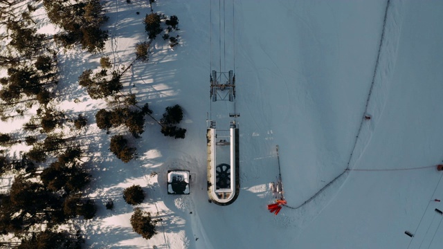 雪山冬季滑雪场的滑雪缆车，供滑雪者和滑雪板者鸟瞰图。俯视图从飞行的无人机滑雪电梯在冬季雪坡工作。视频素材