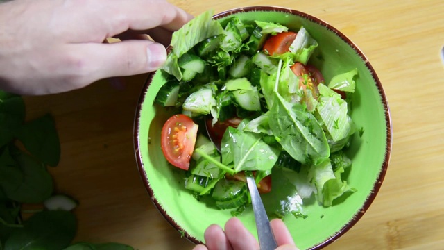 用勺子搅拌蔬菜和香草沙拉。健康饮食视频素材