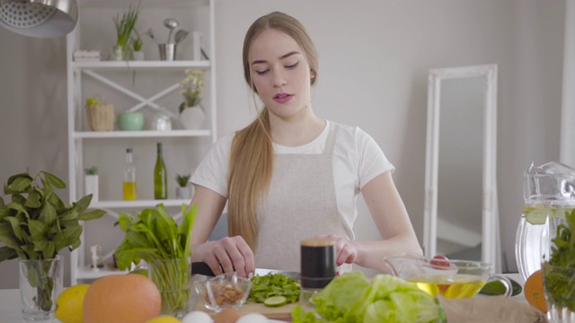 年轻自信的白人妇女在室内切有机沙拉的配料。美丽集中的女孩在家里烹饪素食。健康生活方式，素食主义，健康。视频素材