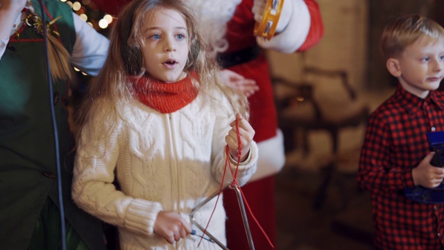 美丽的小女孩和圣诞老人和小精灵一起唱歌跳舞。视频素材