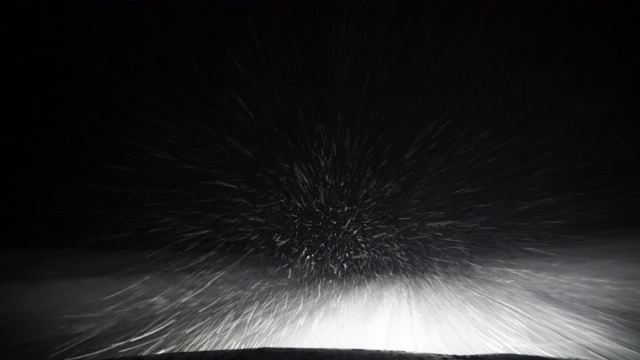 一辆汽车在暴风雪中行驶在夜间的高速公路上视频素材