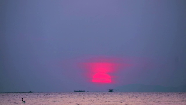 夕阳下，红彤彤的天空落在海面上的云和许多渔船流逝的时间流逝视频素材