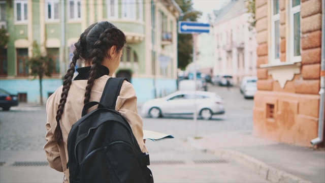 后视图。迷人的年轻黑发与辫子是旅行在欧洲和探索美丽的观光。她转过身来，微笑着。关闭了。副本的空间。4 k。视频素材