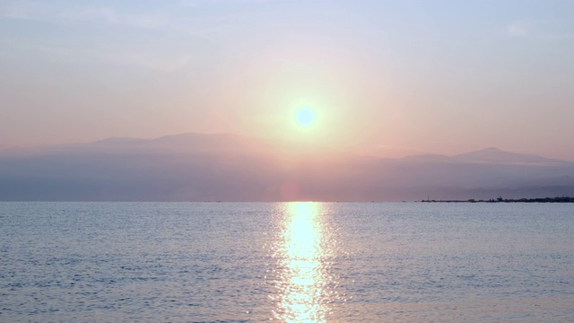 惊人美丽的日出在平静的海面上。黄色的太阳从海和山升起，太阳的路径在水上。阳光和太阳光反射在水面上。金色的光，橙色和金色的蓝天视频素材