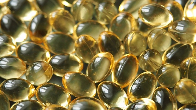 明亮的金黄色的omega-3维生素或鱼油胶囊旋转。关闭了。视频素材