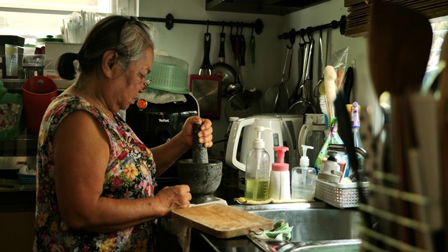 年长的亚洲妇女在家做饭视频素材