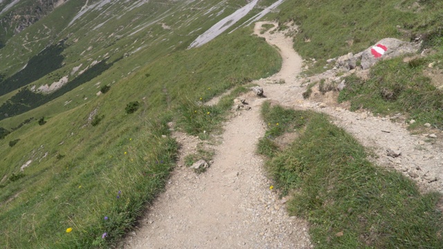 倾斜视角:奥地利因斯布鲁克karendel冰川山，在夏季天空晴朗，云雾密布的Hafelekarspitze-Seegrube步道上徒步旅行的旅行者喜欢冒险的天然小径。视频素材