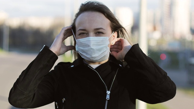 一个戴着医用口罩的女人在城市里的肖像。视频素材