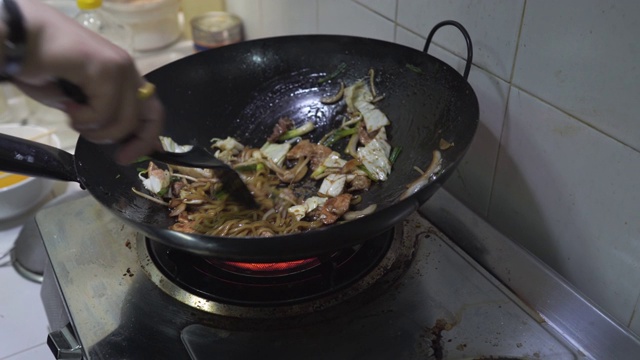 厨师用炒锅炒制日式烧饭的场景特写，蛋肉蔬菜炒鲜面条，食品加工，家常菜，亚洲街头小吃，健康简单的食品，新鲜的配料。视频素材