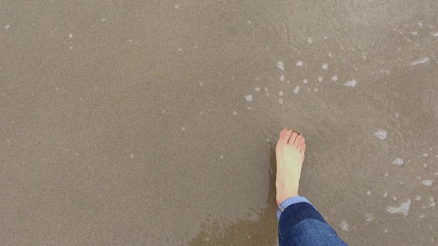 女性光着脚走在海浪中的沙子上。第一人称视角视频下载