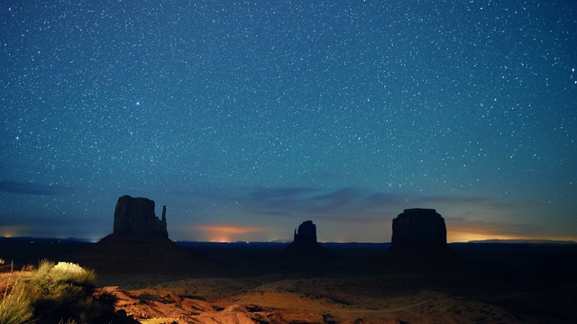 星星和流星的时间流逝在夜空与岩石的轮廓在远处在犹他州/亚利桑那州的纪念碑谷沙漠在晚上视频素材