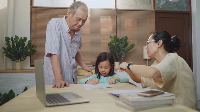 亚洲女儿做家庭作业与她的母亲和祖父帮助和教学在家里视频素材