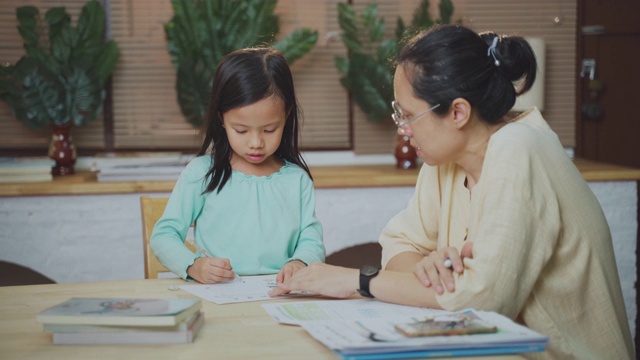 亚洲女儿做家庭作业，而她的母亲在家里帮助和教学视频素材