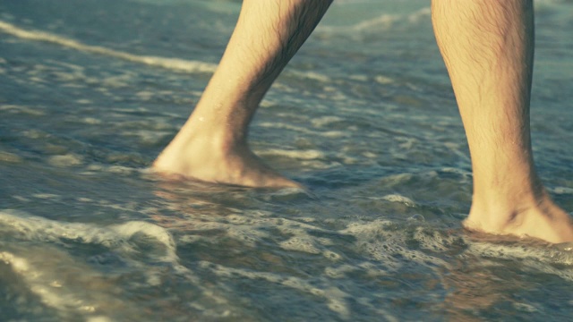 男人的脚在海滩上行走，进入大海视频素材