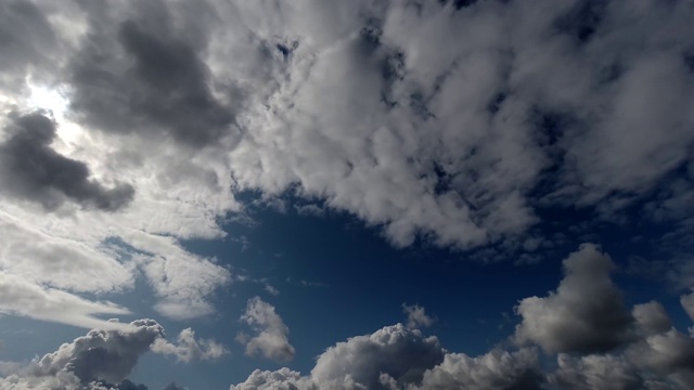 时间流逝:太阳隐藏在蓬松的云后面在天空中飞行。晴朗的白天。4 k视频素材