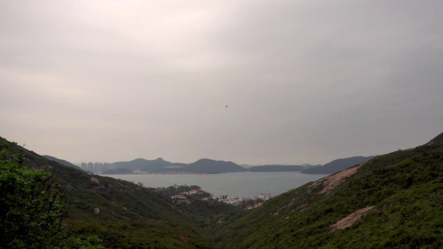 缓慢黄昏，时光流逝的云穿过山谷遥远的房子，山脉和海湾视频素材