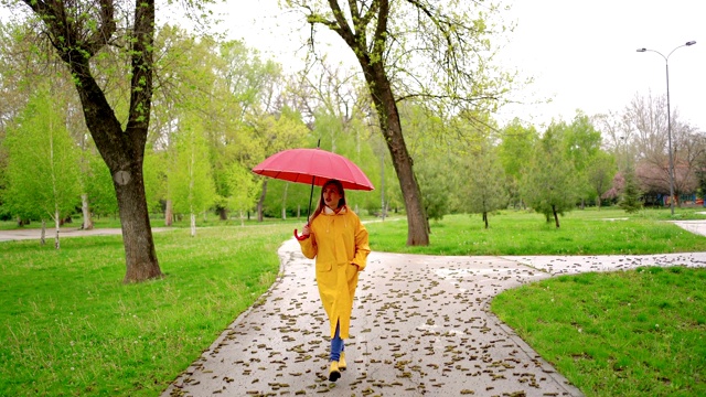 一个年轻女子在雨天在公园里散步视频素材