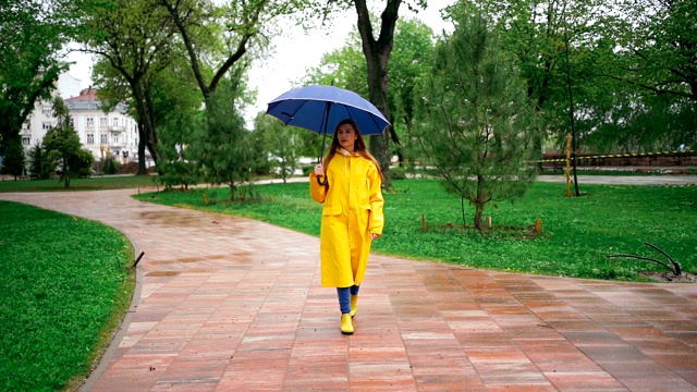 一个年轻女子在雨天在公园里散步视频素材