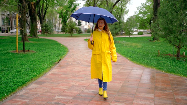 一个年轻女子在雨天在公园里散步视频素材