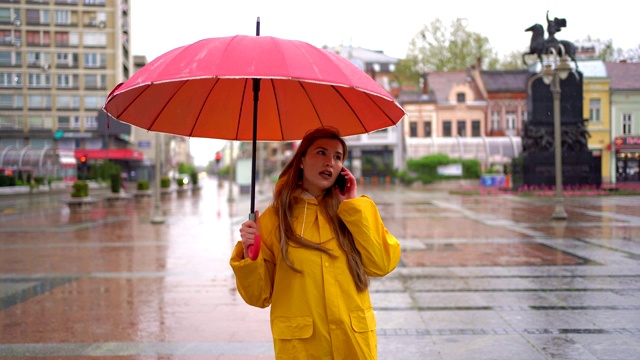 一名年轻女子在雨天一边走路一边打电话视频素材