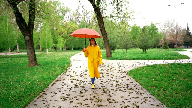 一个年轻女子在雨天在公园里散步视频素材