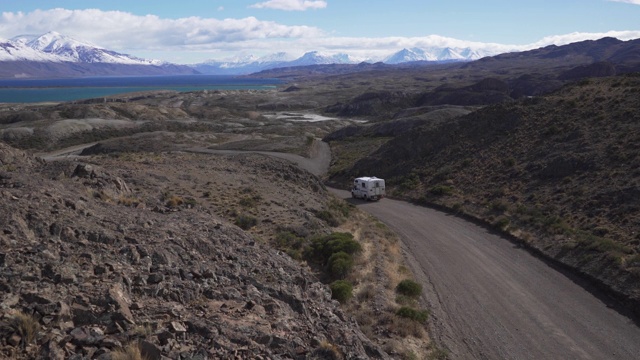 一辆小型露营车正行驶在通往山区湖泊的路上视频素材