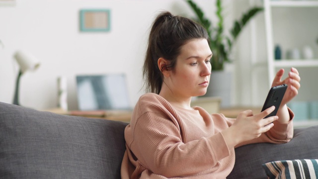 坐在沙发上刷手机的女人视频素材