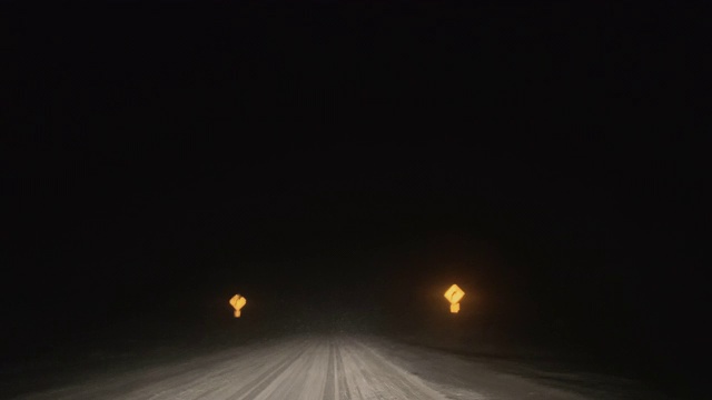 在暴风雪的夜晚沿着道路行驶，同时交替使用远光灯和远光灯(前灯)视频素材