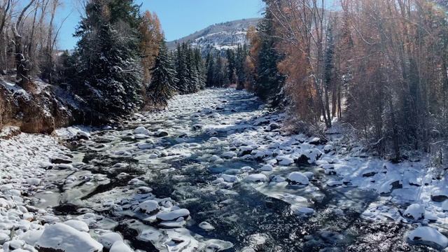 水流下鹰河附近与雪在地面和山脉的背景在一个明亮的冬日附近爱德华兹，科罗拉多州的慢动作拍摄视频素材