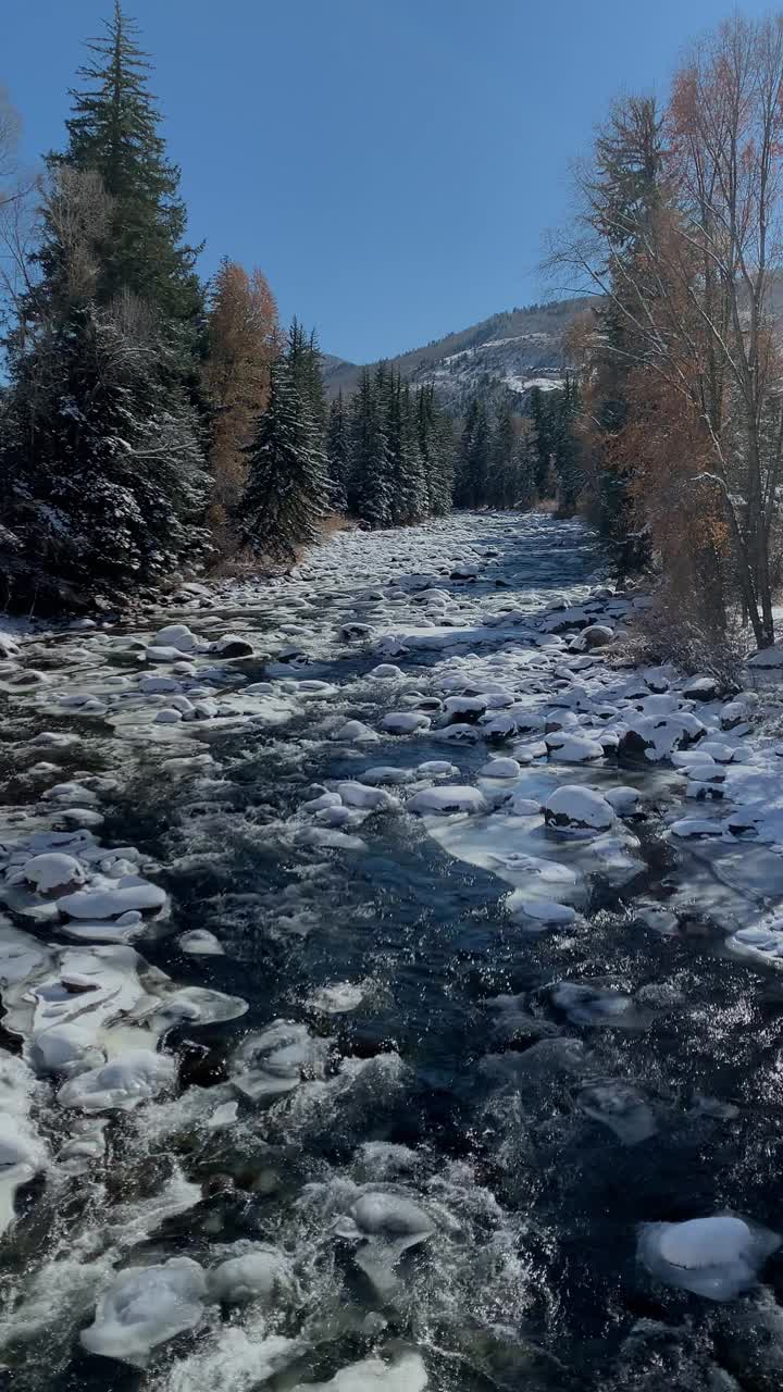 水流下鹰河附近与雪在地面和山脉的背景在一个明亮的冬日附近爱德华兹，科罗拉多州的慢动作拍摄视频素材