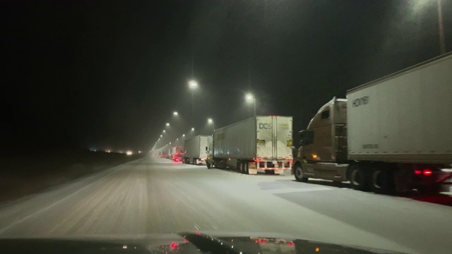 在一个下雪的冬夜，科罗拉多州70号州际公路上，一辆停着的半卡车经过连锁车站视频素材