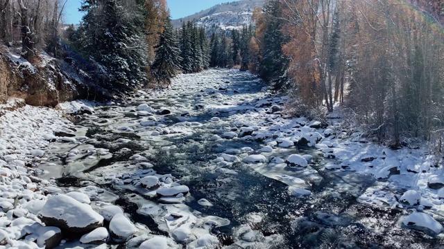 水流下鹰河附近与雪在地面和山脉的背景在一个明亮的冬日附近爱德华兹，科罗拉多州的慢动作拍摄视频素材