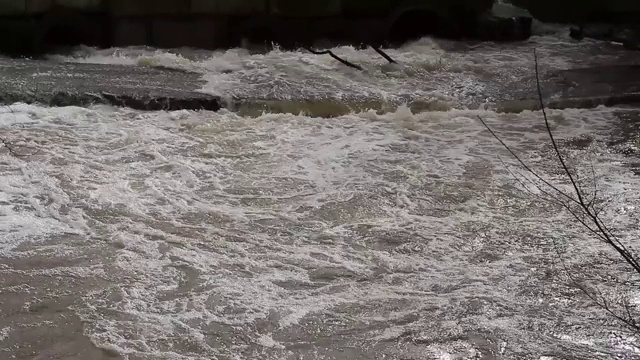 在洪水期间，肮脏的褐色的水淹没了石桥视频素材