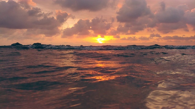 海浪在美丽的夕阳下溅起水花视频素材