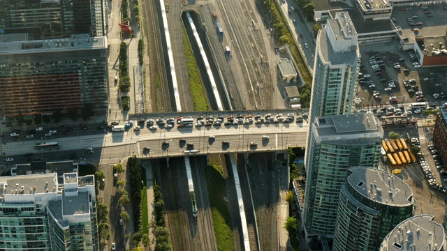 铁路轨道鸟瞰图，火车通过桥下，高层建筑之间的交通视频素材