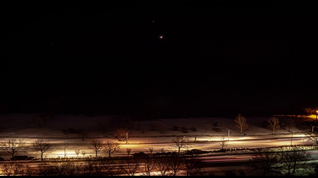 在黑暗的夜空中，飞机灯光在密歇根湖上空排成一列，降落在机场，交通在芝加哥的湖滨大道上急速驶过，创造灯光轨迹。视频素材