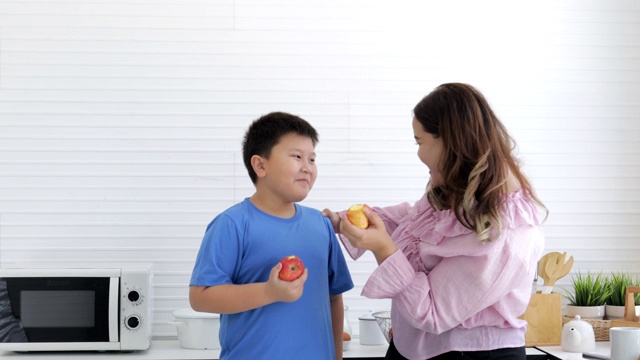 为了减肥瘦身，母子俩一起在厨房里吃着美味有趣的熟苹果。胖女人有健康水果和减肥食品以及低热量水果的概念视频素材