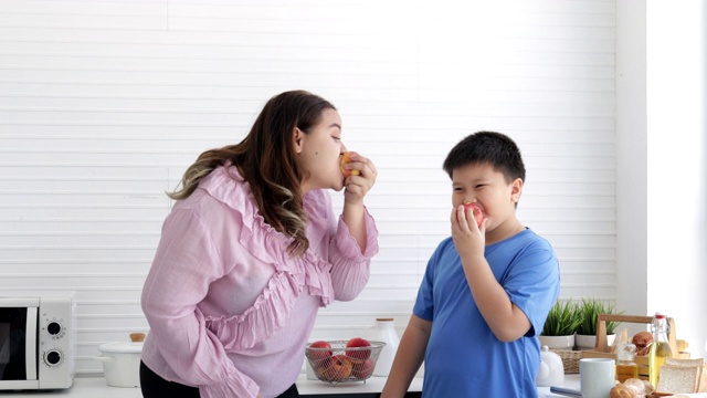 为了减肥瘦身，母子俩一起在厨房里吃着美味有趣的熟苹果。胖女人有健康水果和减肥食品以及低热量水果的概念视频素材