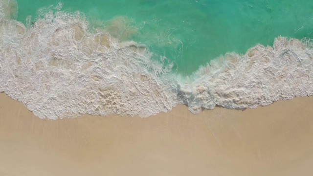 从上到下的鸟瞰图，白色的沙滩与蔚蓝的水，泡沫海浪视频素材