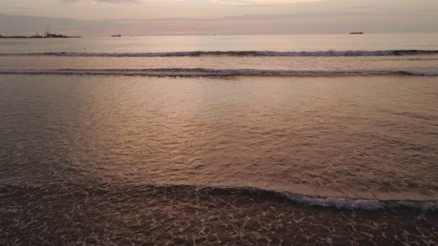 一个女人在海滩上散步，两个男孩在夕阳下玩耍视频素材